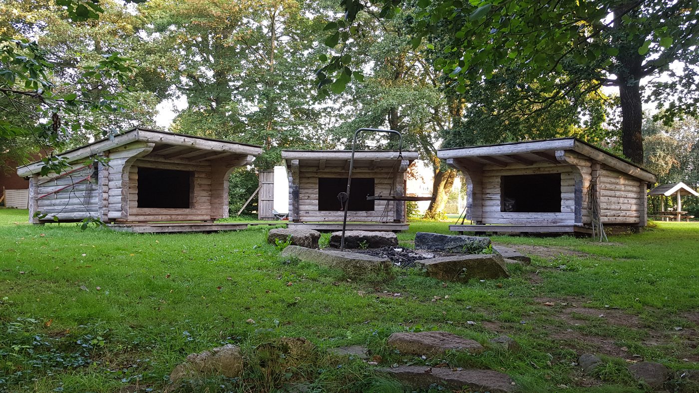 A pair of wooden shelters facing a clearing — Gustes Eng