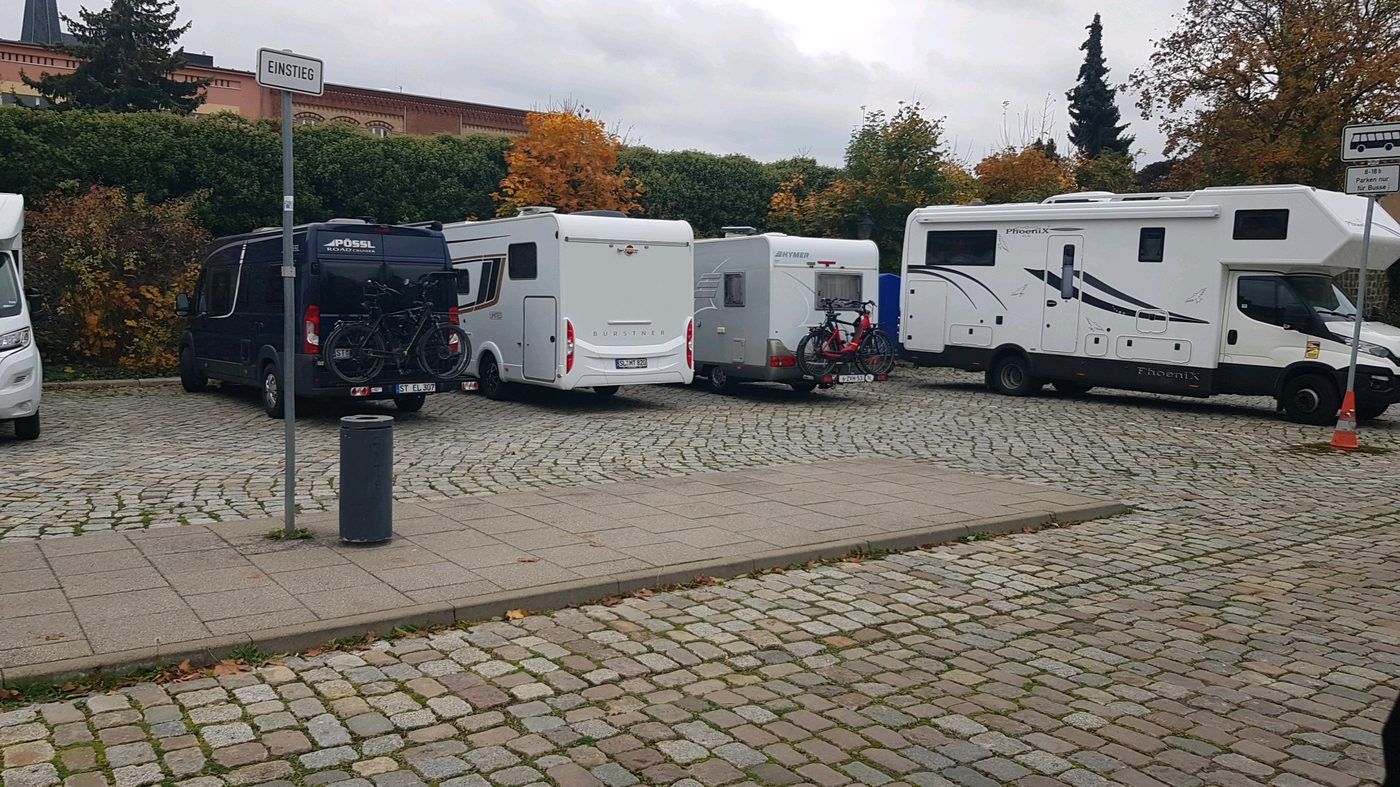 A European motorhome stellplatz — gravel pitches, hookup posts, a few campers parked side by side