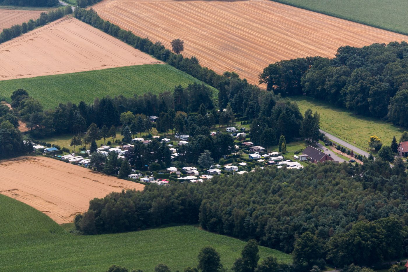 A European campsite with tents pitched on green grass under trees