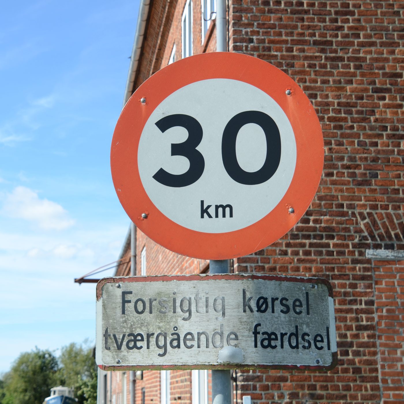 Danish road sign — 30 km/h with crossing-traffic warning on a quiet street